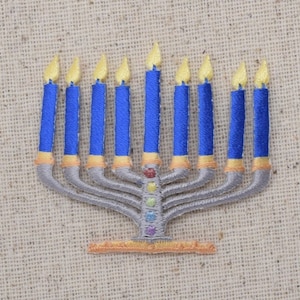 May include: A silver menorah with nine blue candles, each with a yellow flame. The menorah is decorated with colorful gemstones.