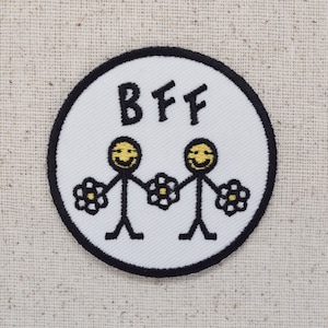 May include: A white circle patch with a black border. The patch has two stick figures holding hands with flowers. The text "BFF" is above the figures.