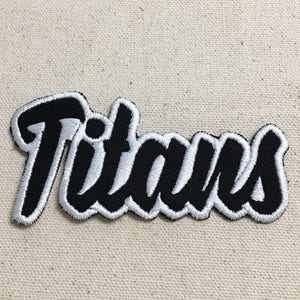 May include: Black and white embroidered patch with the word "Titans" in a stylised font.