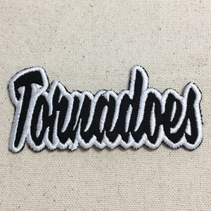 May include: Black and white embroidered patch with the word "Tornadoes" in a stylized font.