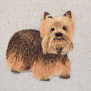 May include: Embroidered patch of a brown and tan Yorkshire Terrier with a fluffy coat and long ears.
