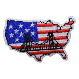 Puede incluir: Un parche bordado con la forma de los Estados Unidos de América con un diseño de bandera americana roja, blanca y azul. Un puente negro se superpone a la bandera, abarcando el país de costa a costa.