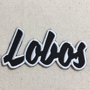 May include: Black and white embroidered patch with the word "Lobos" in a stylized font.