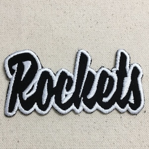 May include: Black and white embroidered patch with the word "Rockets" in a stylized font.
