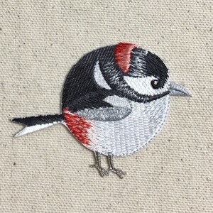 May include: Embroidered patch of a small, gray and black bird with a red head. The bird is facing left and has a small, pointed beak.