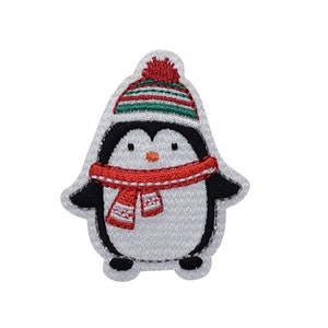 May include: Embroidered patch of a cartoon penguin wearing a red scarf and a striped green and red hat with a red pom-pom. The penguin has black wings and feet, and a white body.
