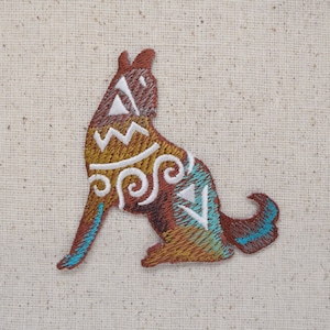 Puede incluir: Parche bordado de un lobo marrón aullando con patrones geométricos blancos y azules.