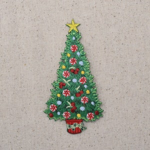 May include: A green felt Christmas tree applique with a yellow star on top. The tree is decorated with red and white candy canes, red berries, and blue and yellow ornaments. The tree is in a red pot with a green bow.