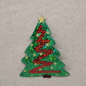 Könnte beinhalten: Ein grüner und roter Weihnachtsbaum-Applik mit goldenen Glitzersternen und Pailletten. Der Baum ist aus Stoff und hat einen goldenen Stern oben drauf.
