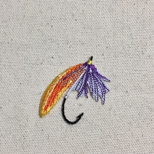 May include: A purple, white, and orange embroidered fly fishing lure with a black hook.