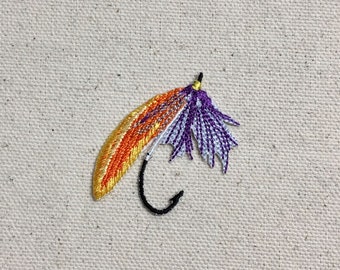 May include: A purple, white, and orange embroidered fly fishing lure with a black hook.