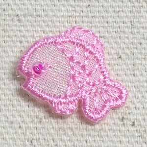 May include: A pink glittery fish-shaped fabric applique with a pink bead for an eye.
