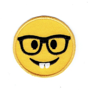 May include: Yellow embroidered iron-on patch of a smiling emoji wearing black-rimmed glasses.