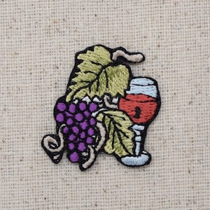Puede incluir: Parche bordado con un racimo de uvas moradas con hojas verdes y una copa de vino tinto.