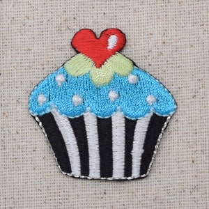 Op de afbeelding: Een blauwe en witte cupcake met een rood hartje erop. De cupcake heeft witte strepen en witte stippen.
