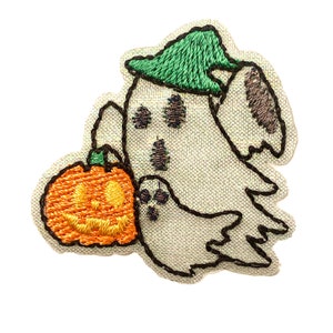 May include: Embroidered patch of a ghost wearing a green hat and holding an orange pumpkin with a jack-o'-lantern face.