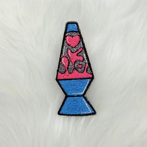 May include: A blue and pink lava lamp with a glitter design. The lamp is shaped like a traditional lava lamp with a round base and a tall, thin neck.