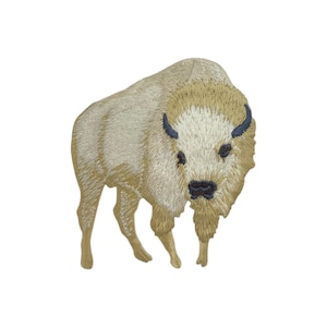 以下が含まれることがあります： 白いバイソンの刺繍パッチ。頭を下げて立っている。バイソンは薄い茶色で縁取られている。