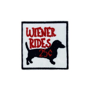 May include: Embroidered patch with a white background and a black border. The patch features the words "WIENER RIDES" in red script above a black dachshund silhouette. Below the dog is the number "25p" in red.