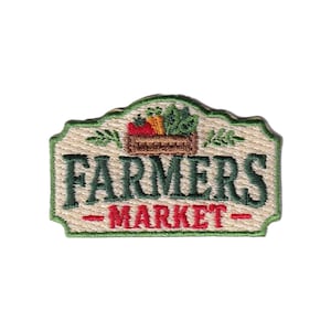 May include: An embroidered patch with a beige background and a green border. It features a brown crate filled with a red tomato, orange carrots, and green leafy vegetables. The text reads FARMERS in dark green and MARKET in red.