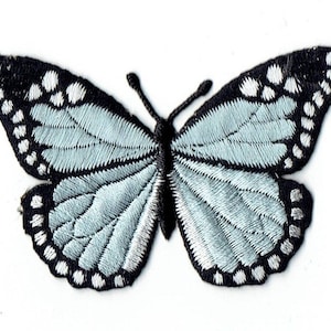 May include: A light blue embroidered butterfly with black and white accents. The butterfly is a popular motif for crafts and decorations.