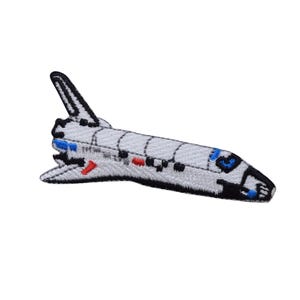 Op de afbeelding: Geborduurde patch van een spaceshuttle in wit, zwart, blauw en rood. De patch heeft gedetailleerde stiksels, die de vleugels, staart en romp van de shuttle afbeelden. Het ontwerp staat tegen een witte achtergrond.