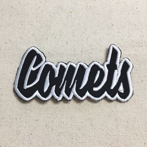 May include: Black and white embroidered patch with the word "Comets" in a stylised font.
