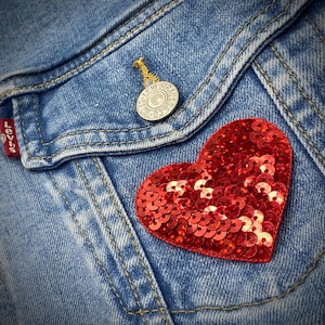 May include: A red sequined heart patch on a blue denim jacket.