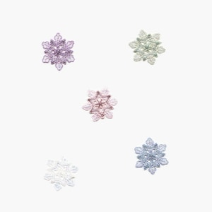 Puede incluir: Cinco delicados adornos de copo de nieve en varios colores, incluyendo morado, rosa, verde, azul y blanco. Los copos de nieve están hechos de encaje y tienen un diseño delicado e intrincado.