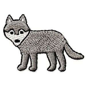 May include: Embroidered patch featuring a gray wolf in a standing pose. The wolf has a white face, black eyes, and a black nose. The patch is outlined in black and is designed to be ironed on or sewn onto fabric.