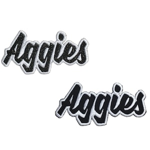 May include: Two black embroidered patches with white outlines that say "Aggies".