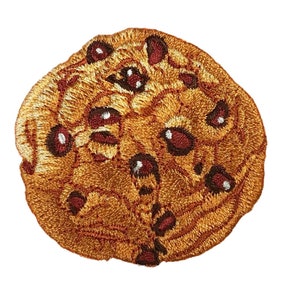 May include: A brown embroidered patch of a chocolate chip cookie with chocolate chips. The cookie is a light brown color with dark brown chocolate chips.