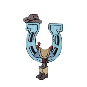 May include: A blue horseshoe with a cowboy wearing a brown hat and boots inside. The cowboy is wearing a yellow vest and blue shirt.