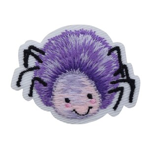 Könnte beinhalten: Gestickter Aufnäher mit einer Cartoon-Spinne mit lila Körper und schwarzen Beinen. Die Spinne hat ein lächelndes Gesicht mit rosa Wangen, vor einem hellblauen Hintergrund. Ideal zum Dekorieren von Kleidung oder Accessoires.