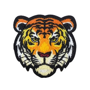 May include: Embroidered iron-on patch of a tiger's face with orange, yellow, and black stripes. The tiger's eyes are black with yellow pupils.