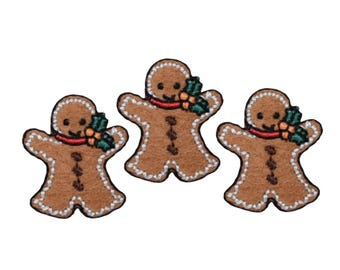 May include: Three brown gingerbread man felt appliques with white icing and red candy smiles. Each gingerbread man has a green holly sprig with red berries.