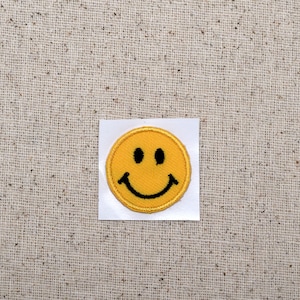 May include: A yellow smiley face patch with a black outline. The patch is on a white background.