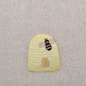 May include: A yellow embroidered beehive with a black and yellow bee on the front.