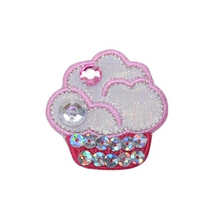 May include: A pink and white cupcake with a sparkly frosting and red sequin trim. The cupcake has a pink gem on top.