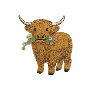 May include: An embroidered patch featuring a brown Highland cow with long, curved horns. The cow is holding a small bouquet of white and pink flowers with green stems in its mouth. The design uses detailed stitching to show the fur texture.