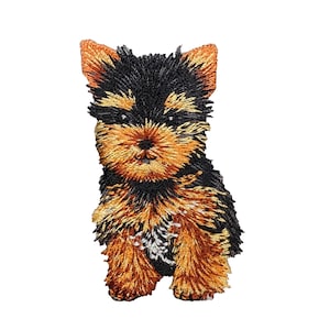 May include: Embroidered patch of a Yorkshire Terrier puppy with black, brown, and tan fur. The puppy is standing with its paws together and looking directly at the viewer.