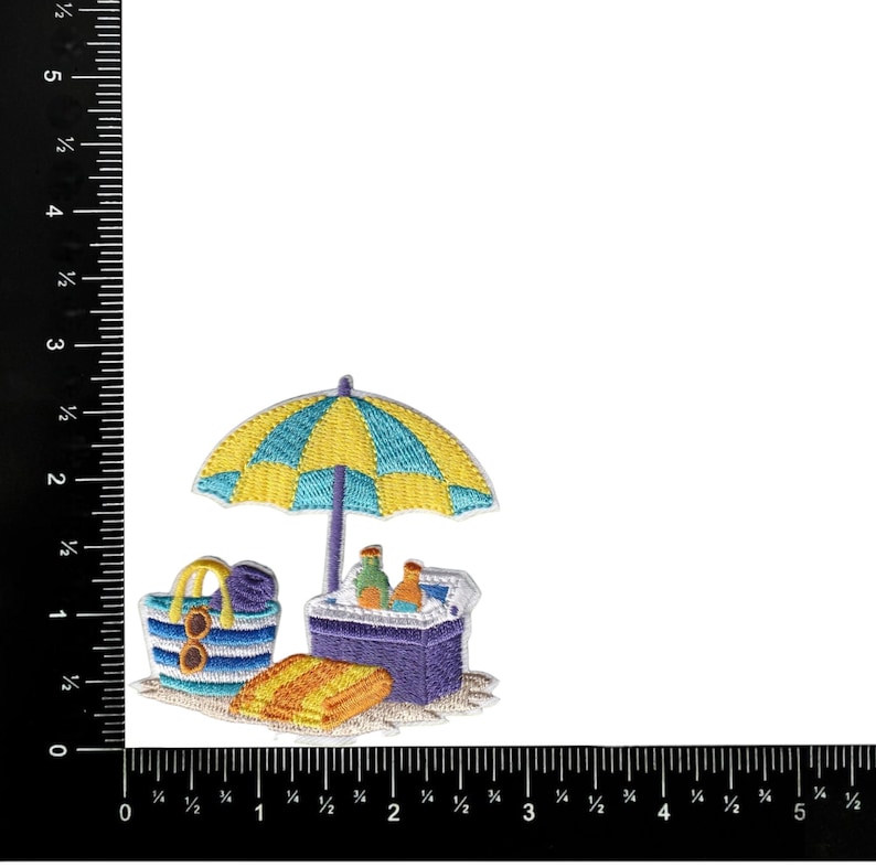 May include: Embroidered patch featuring a beach scene with a yellow and blue striped umbrella, a cooler, a beach bag, and a towel. The beach bag has sunglasses and a hat. The cooler has two bottles. The patch is on a white background.