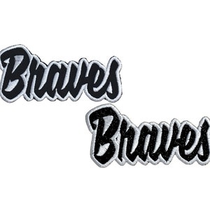 May include: Two black embroidered patches with white outlines that say "Braves" in a stylised font.