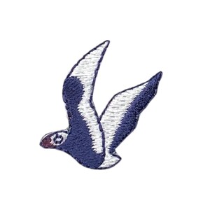 May include: A blue and white embroidered seagull patch. The seagull is flying with its wings spread out.