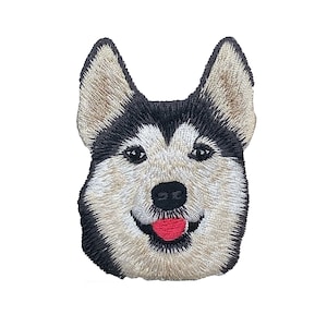 Puede incluir: Parche bordado con la cara de un perro husky. El perro tiene pelo blanco y negro, una lengua rosa y una expresión amigable.