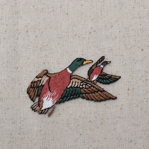 May include: Embroidered patch of two mallard ducks in flight. The ducks are brown, green, and white with detailed stitching.