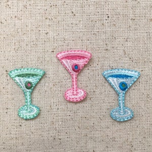 Puede incluir: Tres parches bordados de vaso de martini en rosa, verde y azul con una pequeña aceituna en cada vaso.