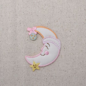 May include: A white crescent moon with a pink bow, a pink sleeping cap, and a yellow star with a smiling face. The moon has a pink outline and a smiling face with pink cheeks.