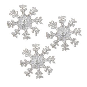 Puede incluir: Tres copos de nieve plateados con purpurina, cada uno con una forma de estrella de seis puntas y detalles intrincados. Los copos de nieve están aislados sobre un fondo blanco.