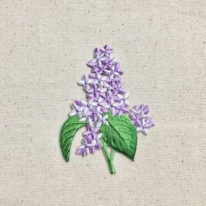 May include: Purple and white embroidered lilac flower patch with green leaves.